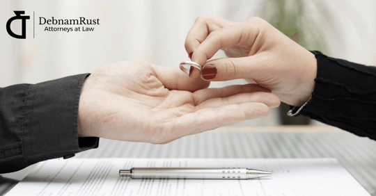 woman putting wedding ring back in palm of another person's hand with paper and pen below them