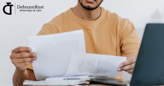 man looking at paperwork in front of his computer