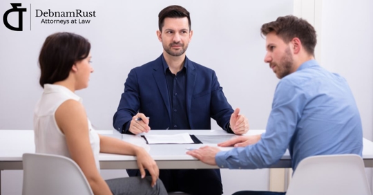 man and woman sitting with a third party mediator having a serious discussion