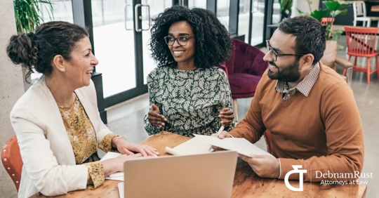young couple sitting with attorney holding paperwork and smiling