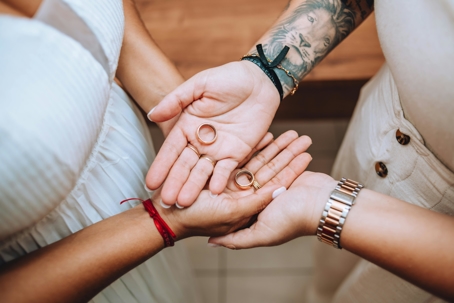 Close-up of two people holding wedding rings together in their palms, symbolizing love and unity.