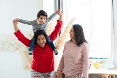 Happy family scene with two mothers and their son enjoying playful bonding time indoors