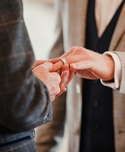 an LGBTQ+ male couple holding wedding bands together