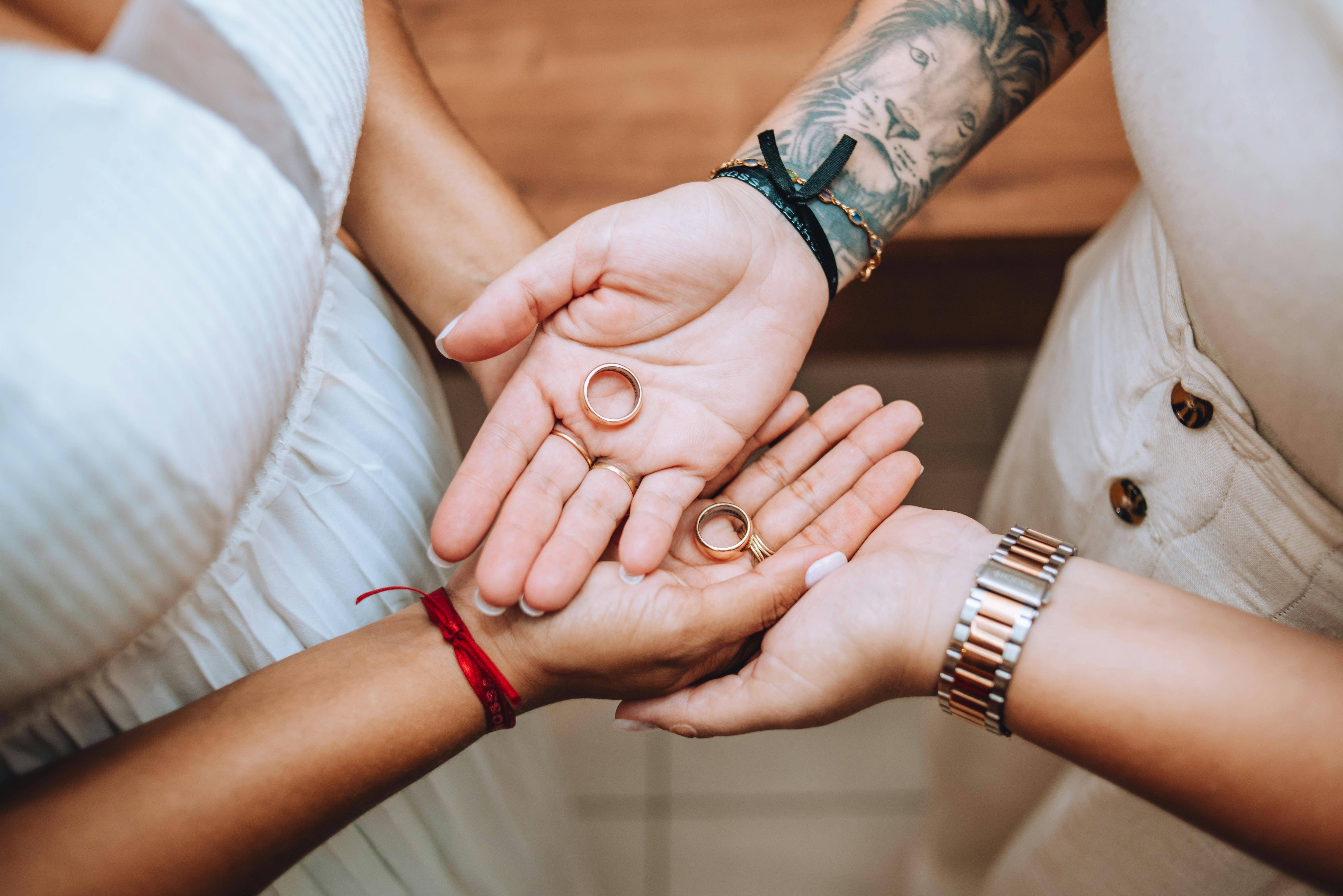 Close-up of two people holding wedding rings together in their palms, symbolizing love and unity.