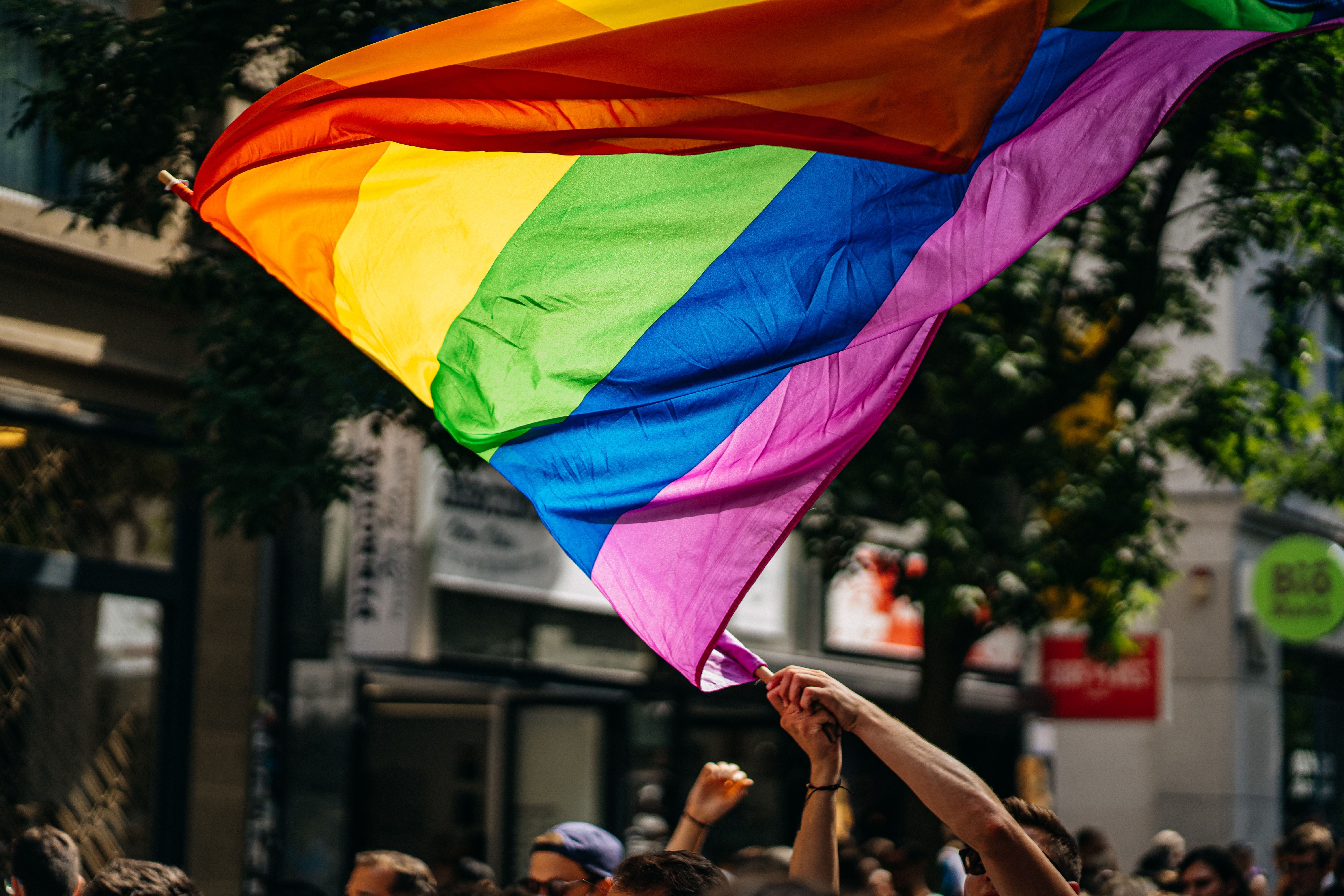 person waving pride flag at rally